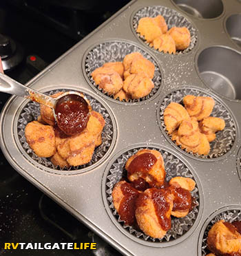 Adding brown sugar, cinnamon and metled butter to the top of each monkey bread cupcake before putting in the oven to bake